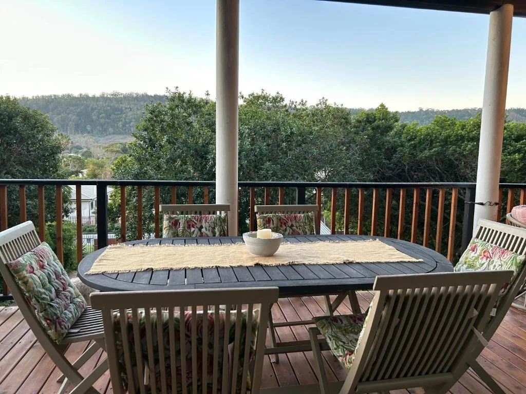 Spacious deck with dining table overlooking forested hills and lagoon views