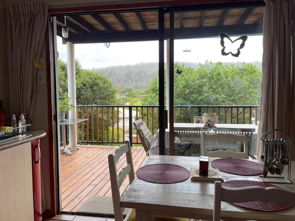 Covered deck with dining table overlooking forested valley and hills
