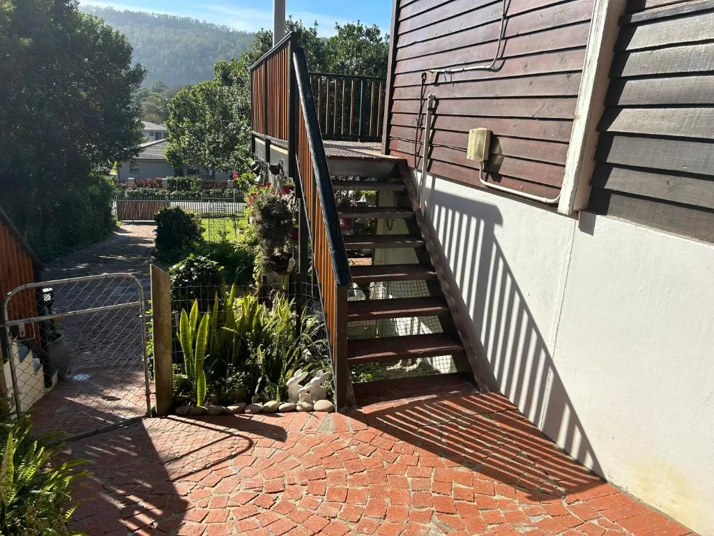 Brick pathway leading to wooden deck stairs with mountain backdrop