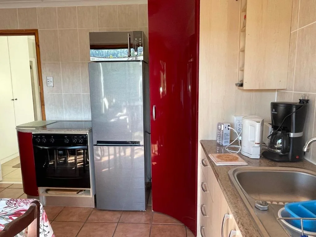 Kitchen with stove, refrigerator, sink, and red cabinetry