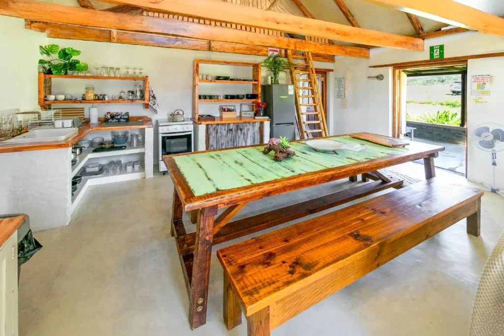 Open-plan kitchen and dining area with wooden beamed ceiling and green table