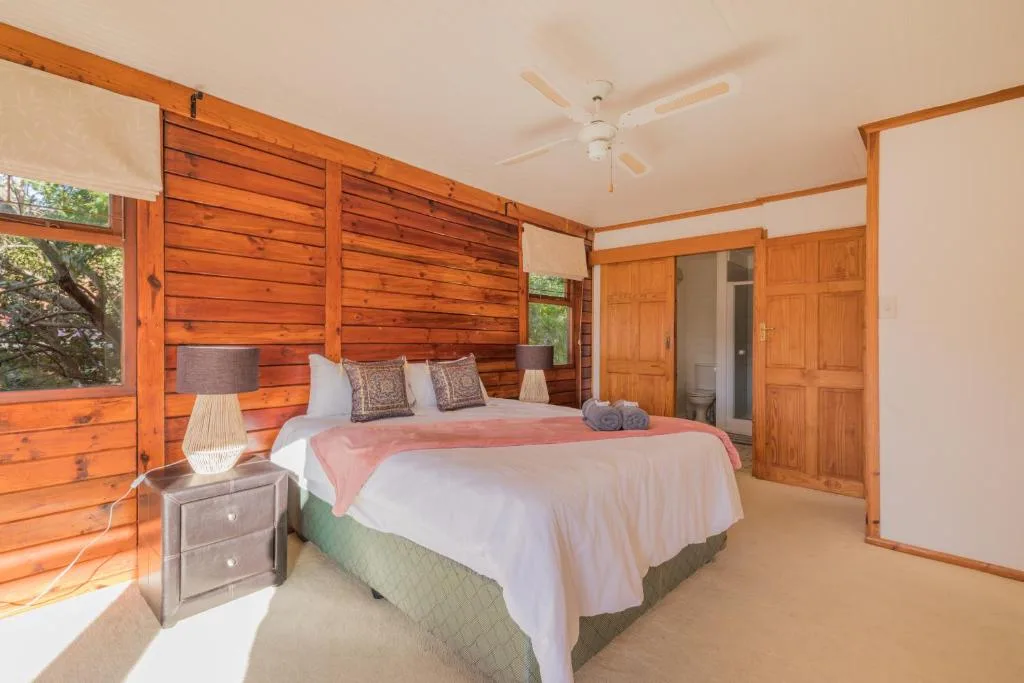 Spacious bedroom with wooden beams, queen bed, and garden views