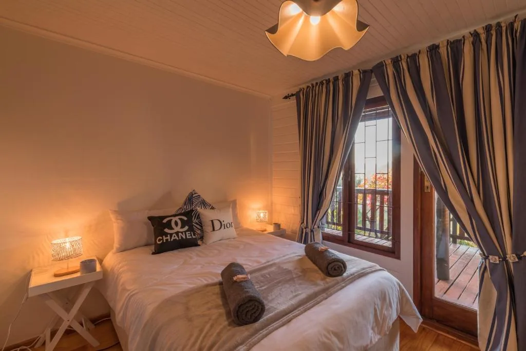 Spacious bedroom with queen bed, designer pillows, warm lighting, and deck access