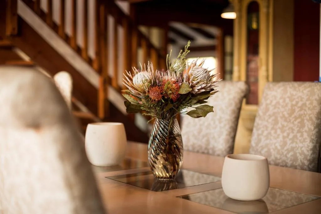 Elegant floral arrangement with proteas in glass vase on dining table