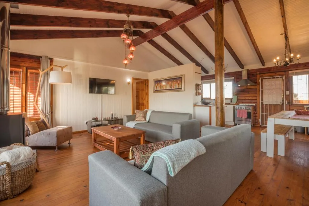 Open-plan lounge with gray sofas, wooden beams, and exposed brick fireplace