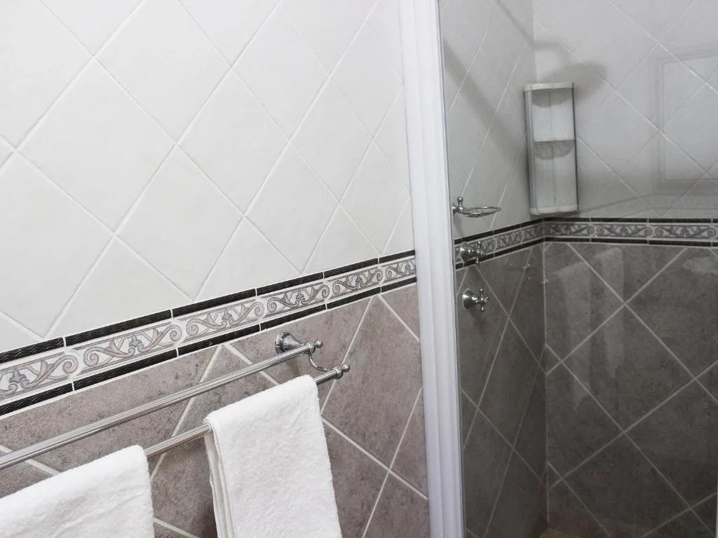 Modern bathroom with tiled walls, towel rails, and chrome fixtures
