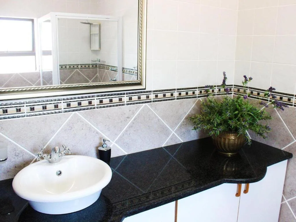 Modern bathroom vanity with round sink, black countertop, decorative mirror