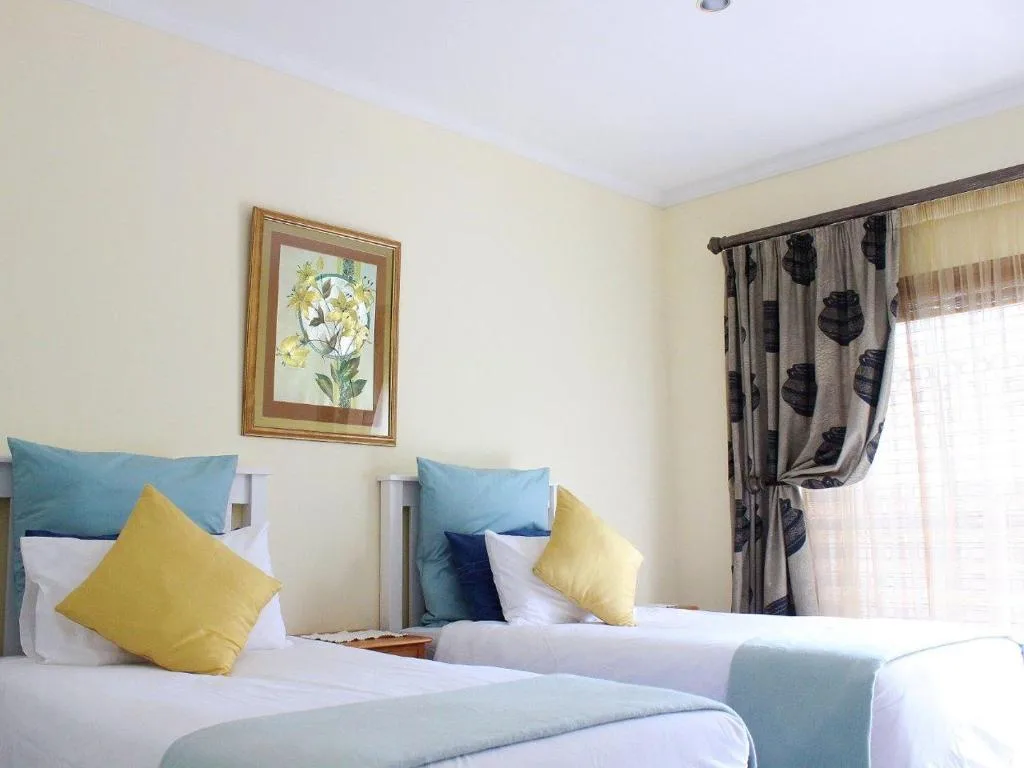 Bright bedroom with two single beds, yellow pillows, and patterned curtains
