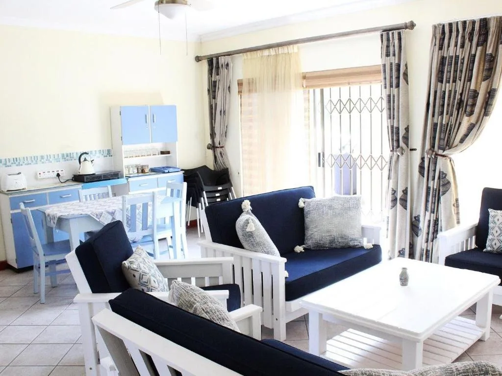 Open-plan lounge with navy sofas, white wooden frames, and coastal decor