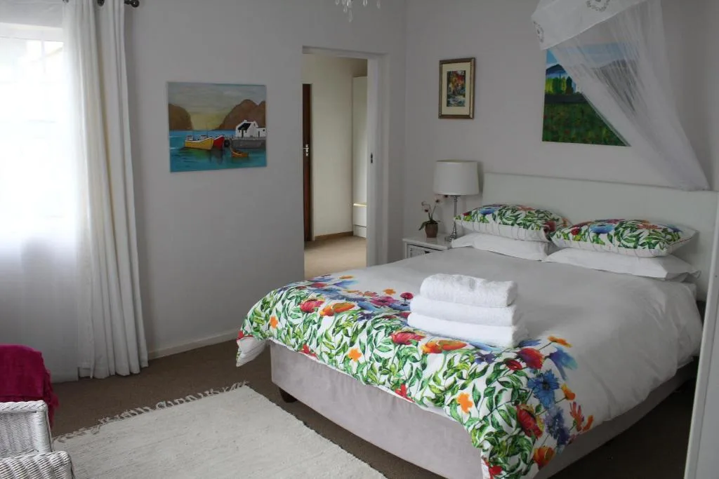 Bright bedroom with twin beds, colorful floral bedding, and coastal artwork
