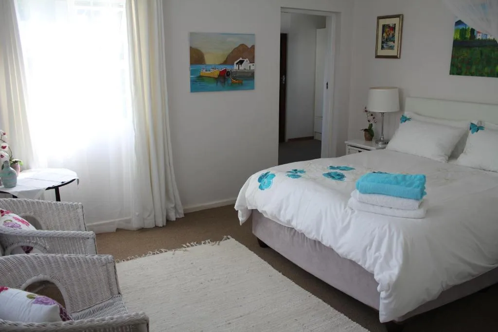 Bright bedroom with white bedding, turquoise accents, and coastal artwork
