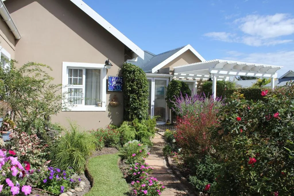 Modern cottage exterior with white pergola, lush flowering garden, and manicured landscaping