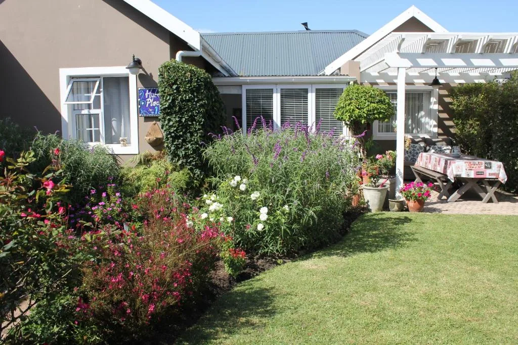 Front garden with flowering plants and manicured lawn, cottage exterior visible