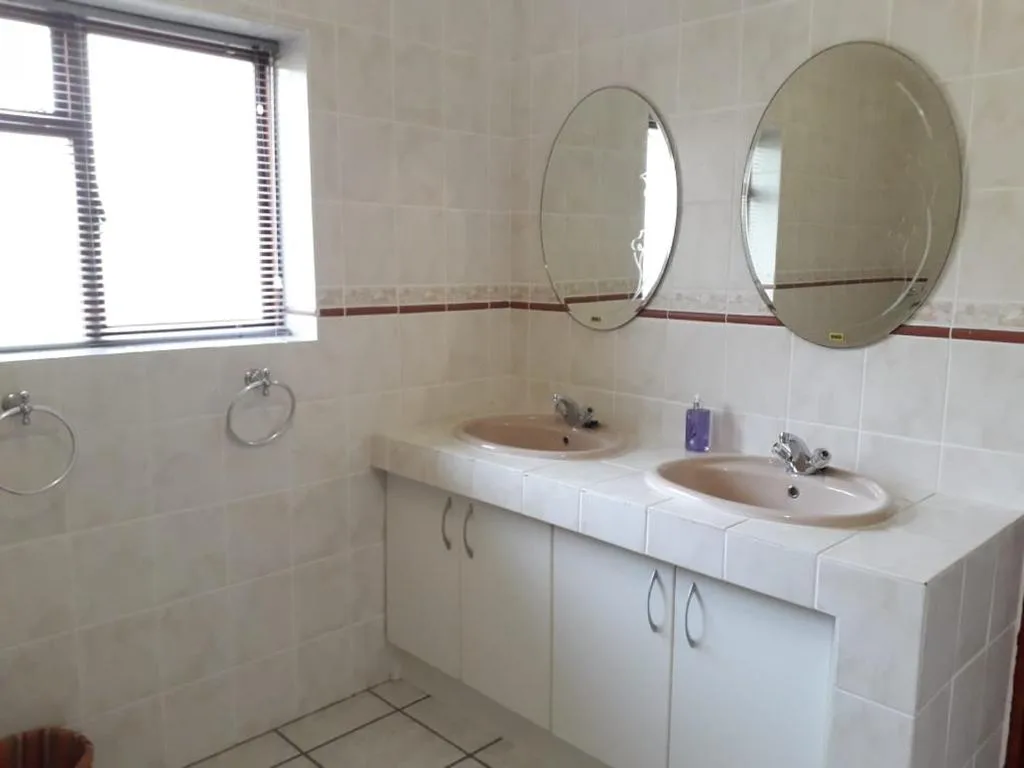 Bright bathroom with dual vanity sinks and round mirrors above
