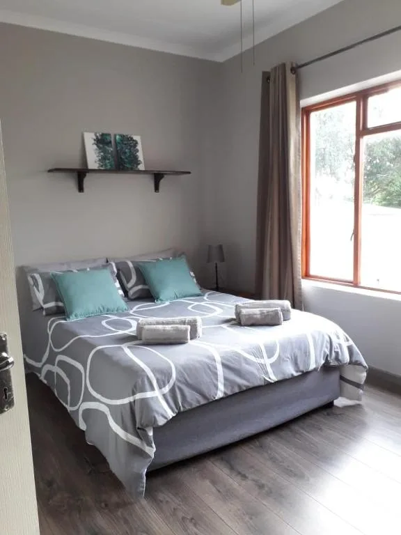 Comfortable bedroom with modern bedding, turquoise pillows, and garden views