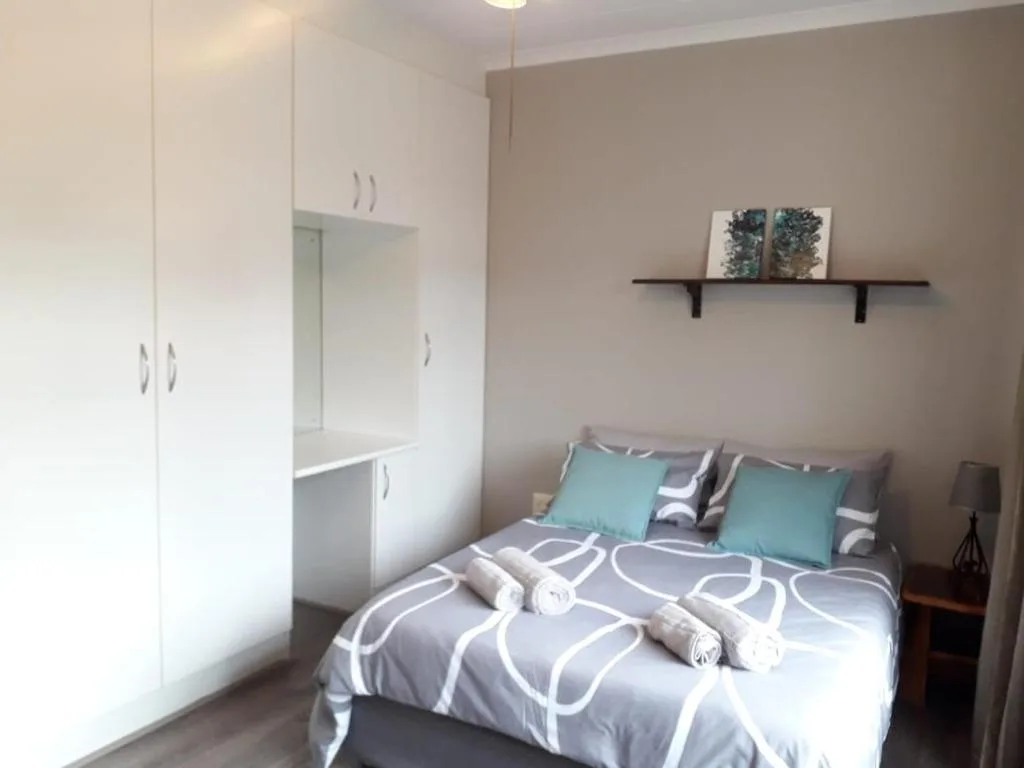 Modern bedroom with queen bed, turquoise pillows, and built-in white wardrobes