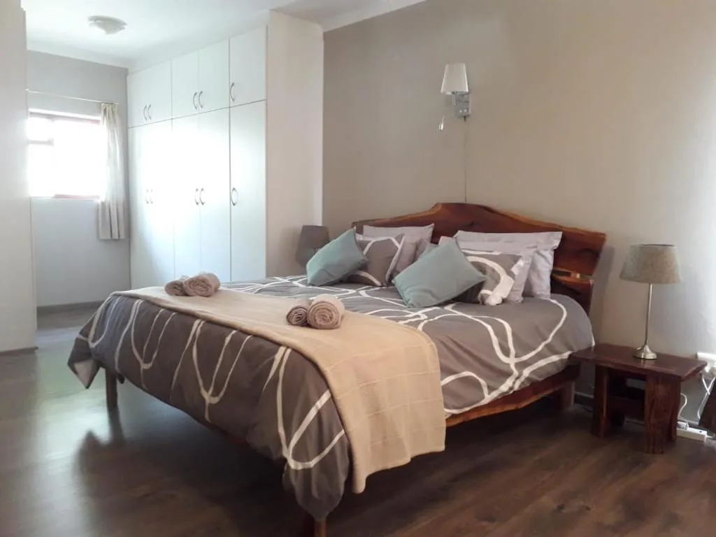 Spacious bedroom with wooden bed, white cabinetry, and warm neutral tones