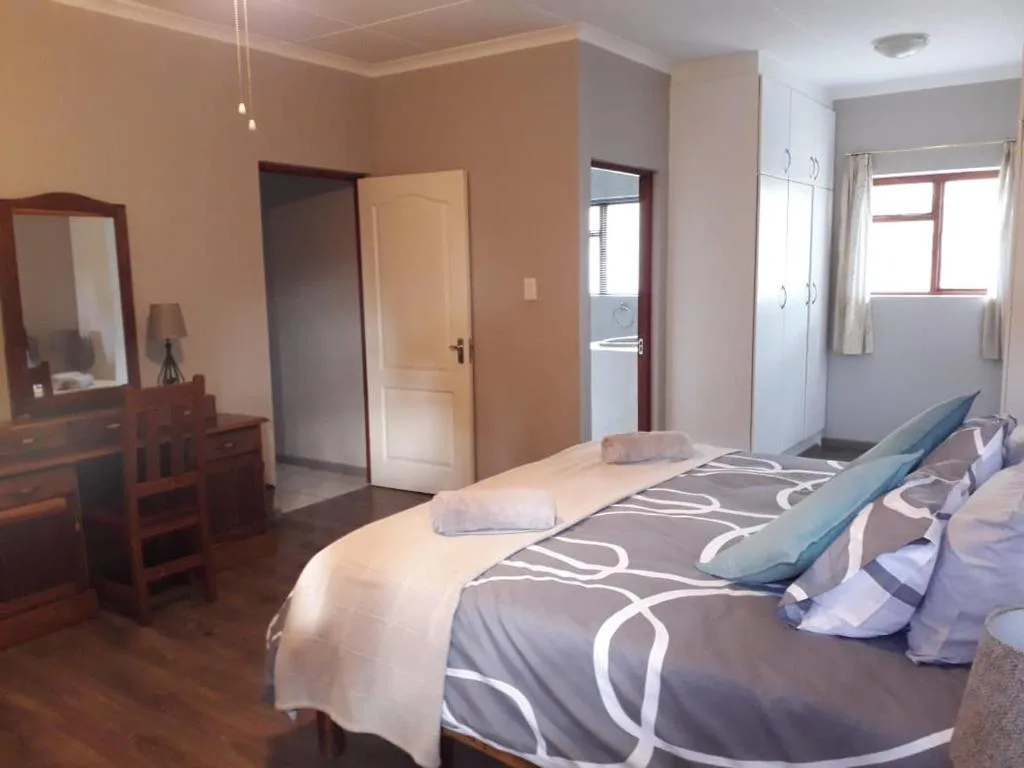 Spacious bedroom with twin beds, wooden vanity, and en-suite bathroom access