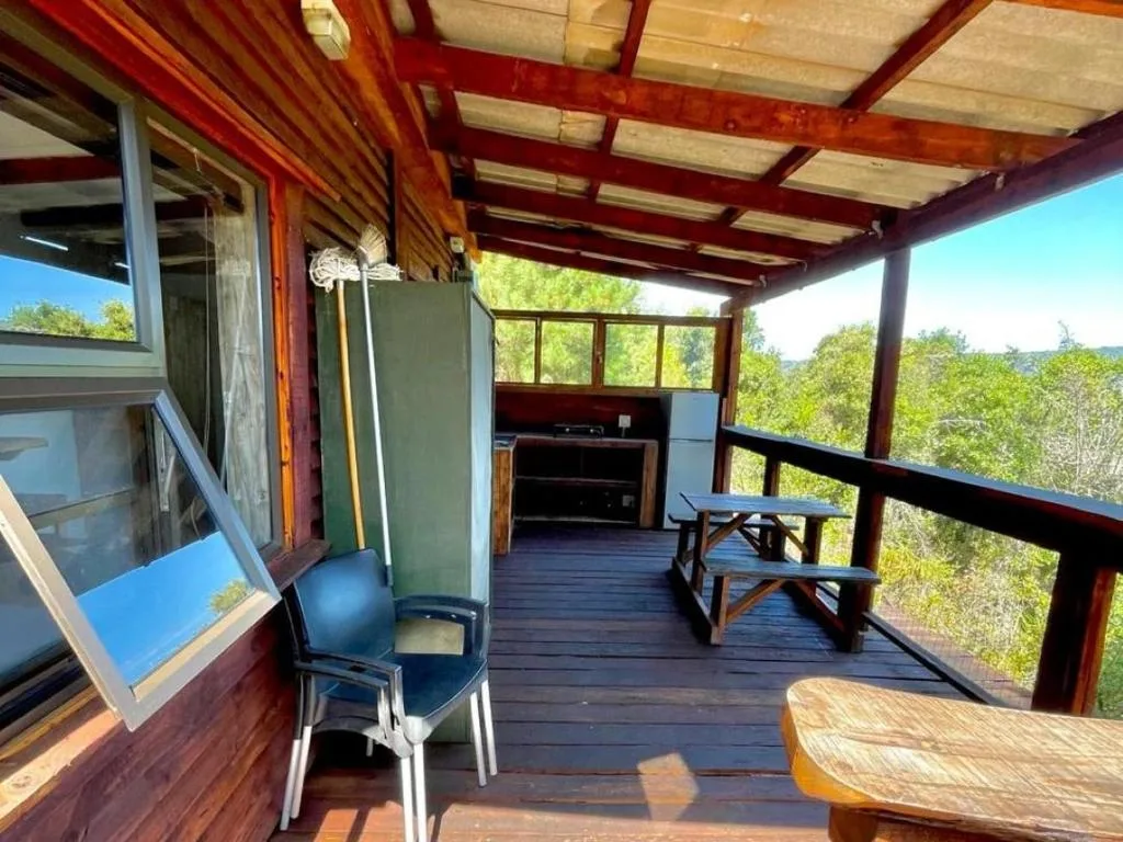 Covered deck with braai, seating, and forest views from property
