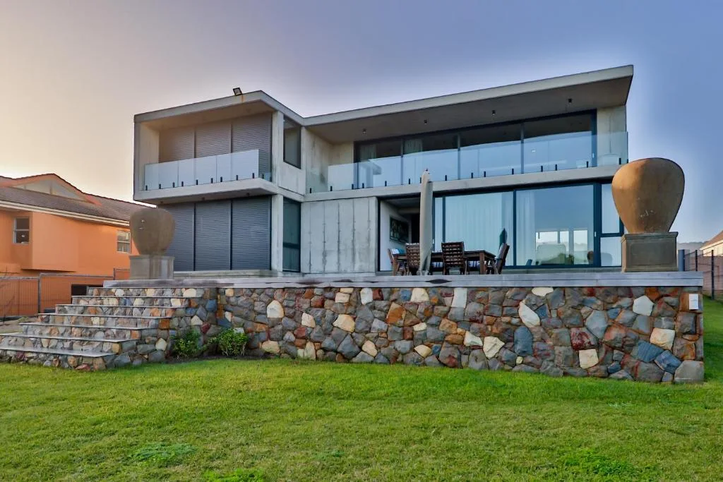 Modern two-story beach house with stone foundation and glass balconies