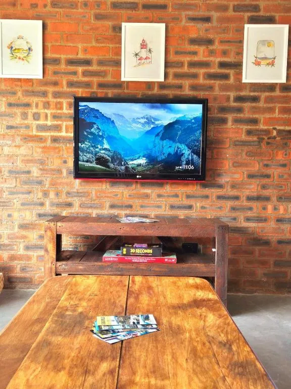 Living room with mounted TV on exposed brick wall and wooden table