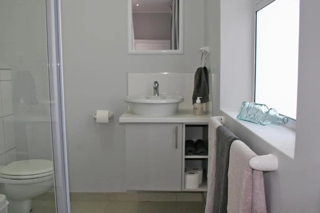 Modern bathroom with round vessel sink, toilet, shower enclosure, and window