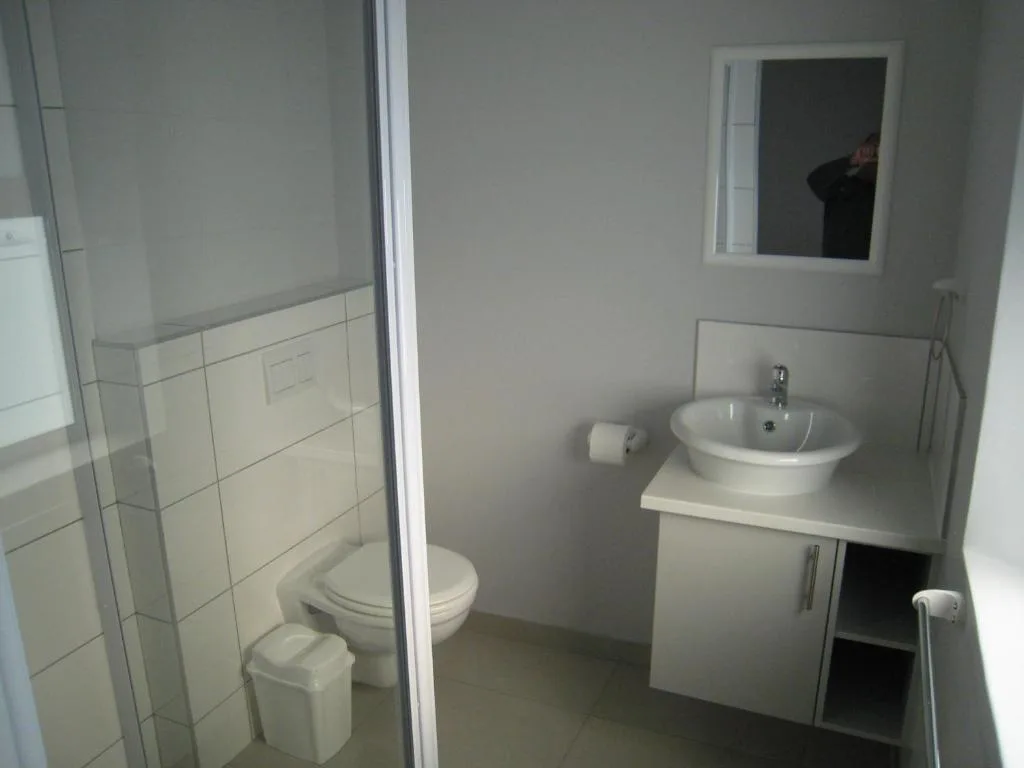 Clean bathroom with toilet, round sink vanity, and mirror