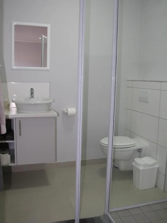 Modern bathroom with round sink vanity, mirror, and separate toilet area