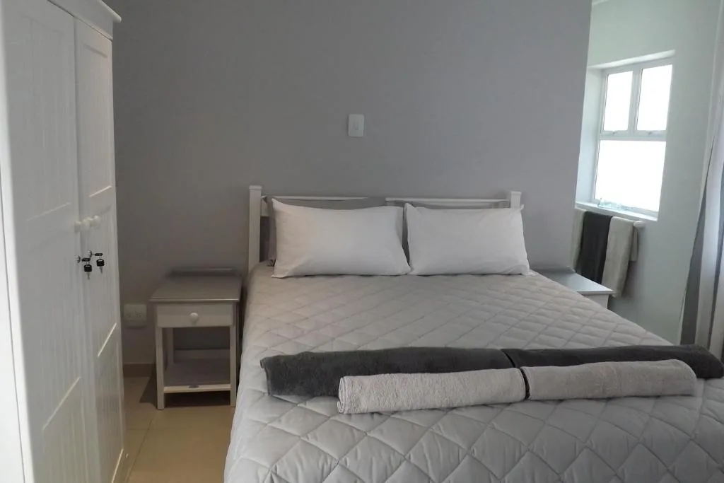Bright bedroom with queen bed, white pillows, and natural window light