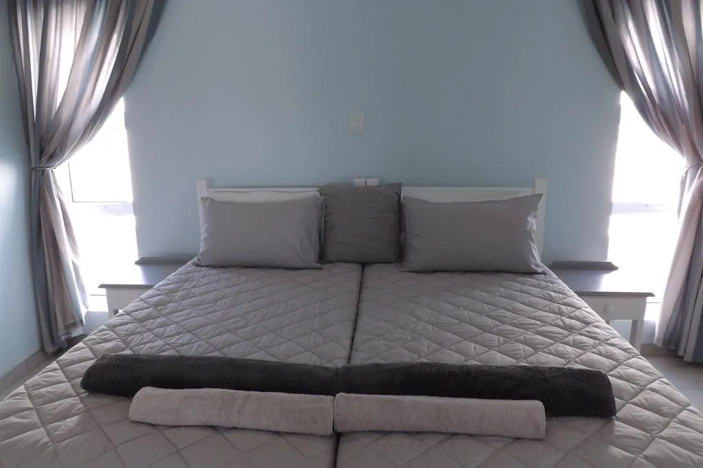 Bright bedroom with made double bed, gray bedding, and large windows