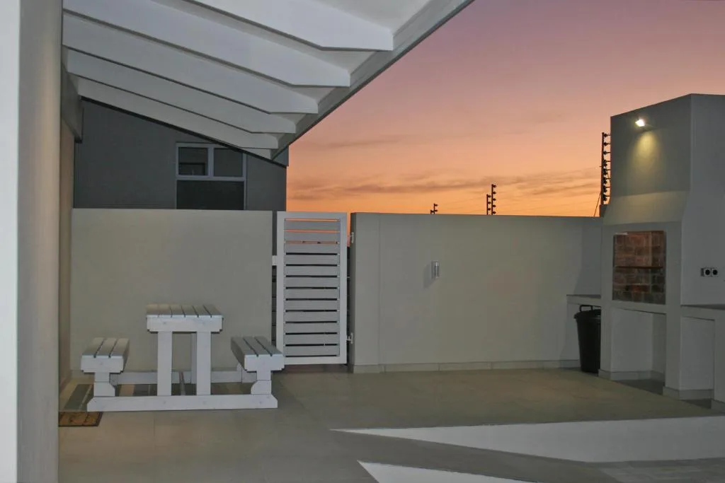 Covered rooftop patio at sunset with benches and city lights