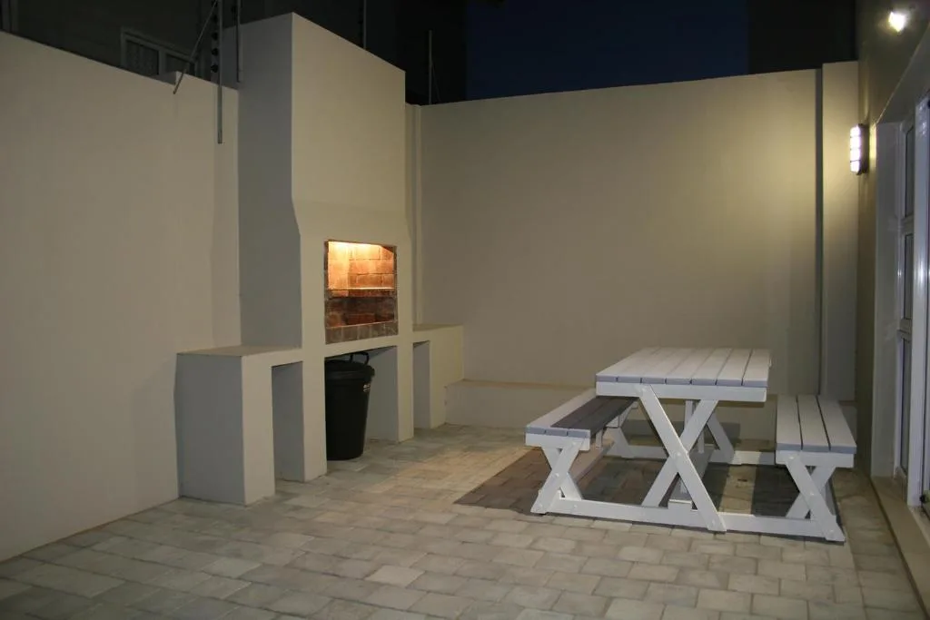 Enclosed patio area with white picnic table and built-in braai fireplace