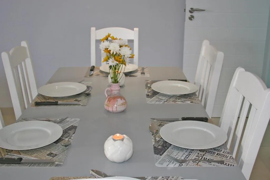 Elegant dining table set for four with white chairs and fresh flowers
