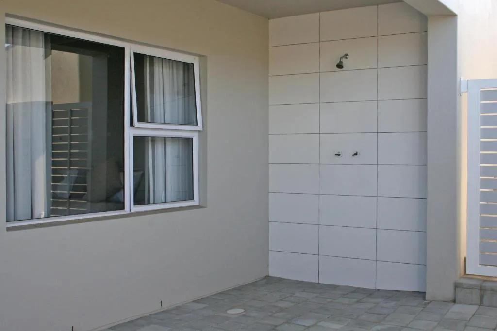 Modern apartment exterior with white tiled wall and large window doors
