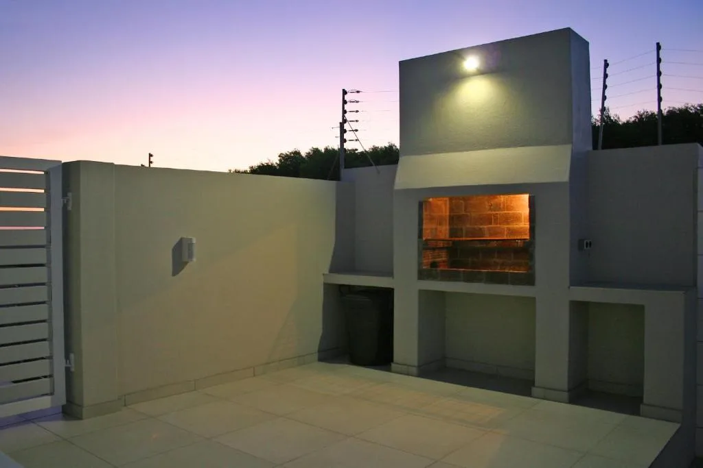Modern apartment building exterior at dusk with illuminated entrance and concrete patio