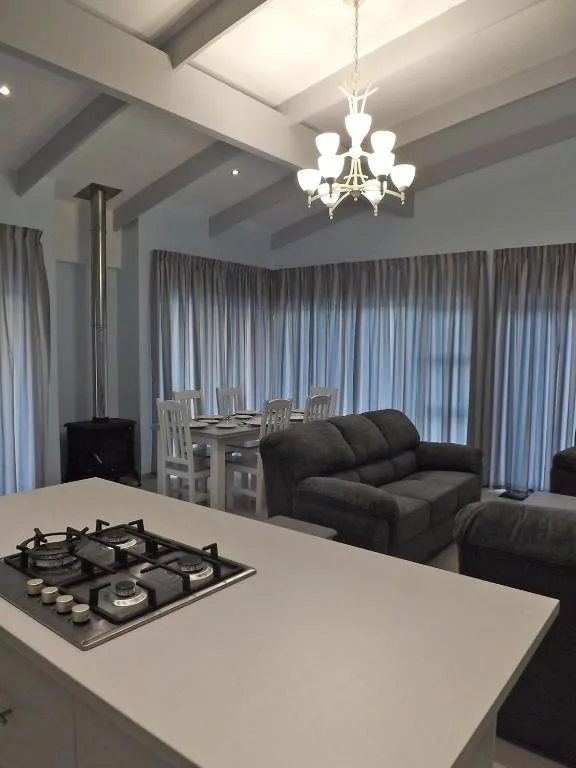 Modern open-plan lounge with black sofa, gas cooktop, and dining area