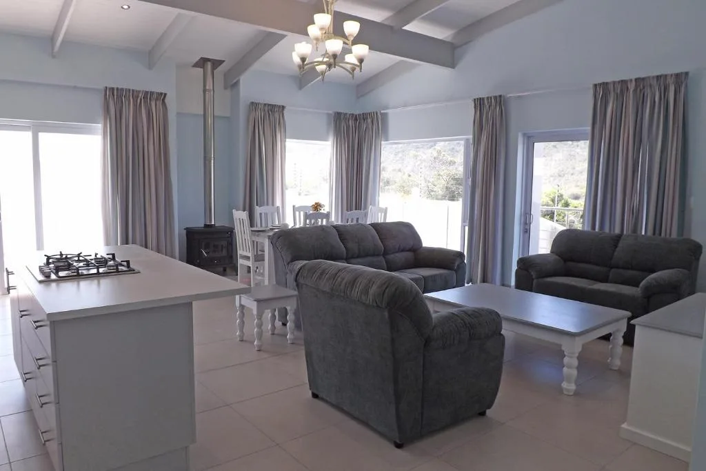Open-plan lounge with dark sofas, fireplace, and multiple glass doors overlooking garden