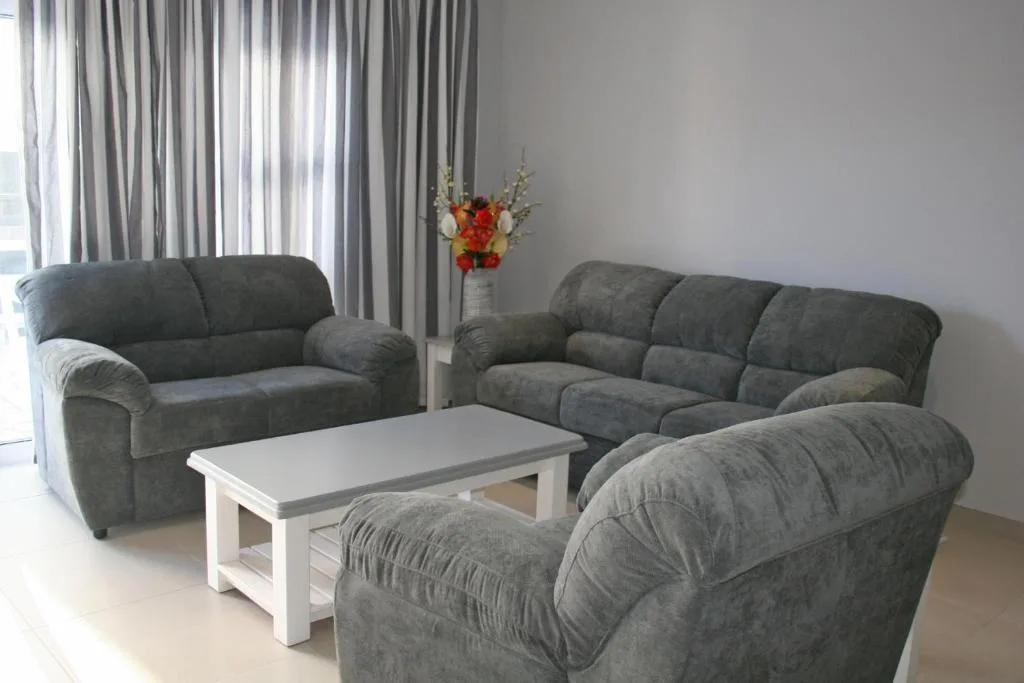 Modern lounge with gray upholstered sofas and armchair around white coffee table