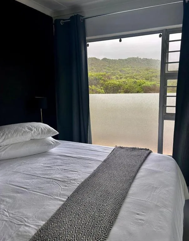 Modern bedroom with white bedding overlooking lush green mountains