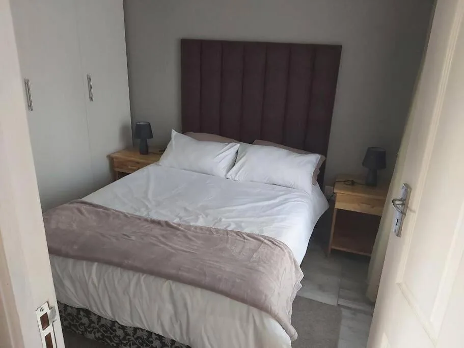 Clean bedroom with queen bed, burgundy headboard, white linens, wooden nightstands