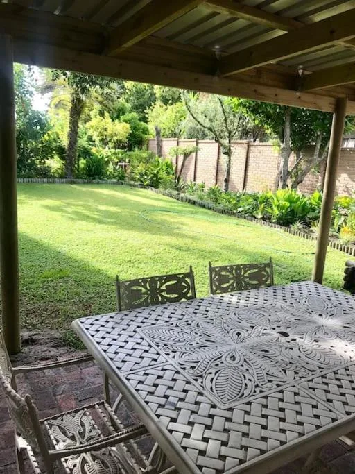 Covered patio with dining table overlooking manicured garden lawn