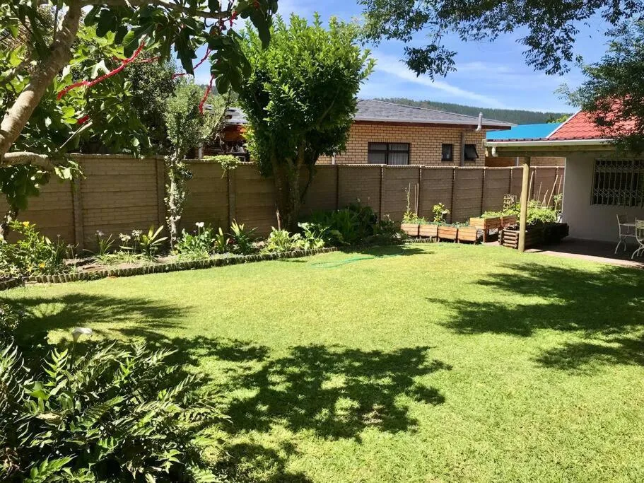 Lush green garden with brick cottage, mature trees, and peaceful outdoor setting