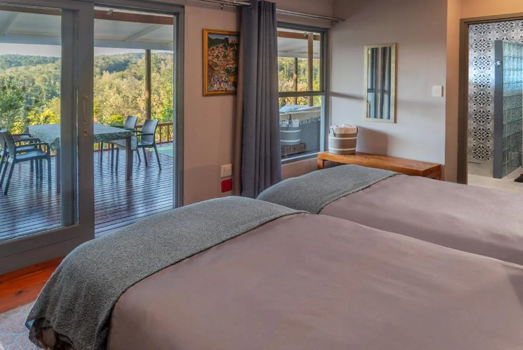 Spacious bedroom with double bed, deck access, and forest views