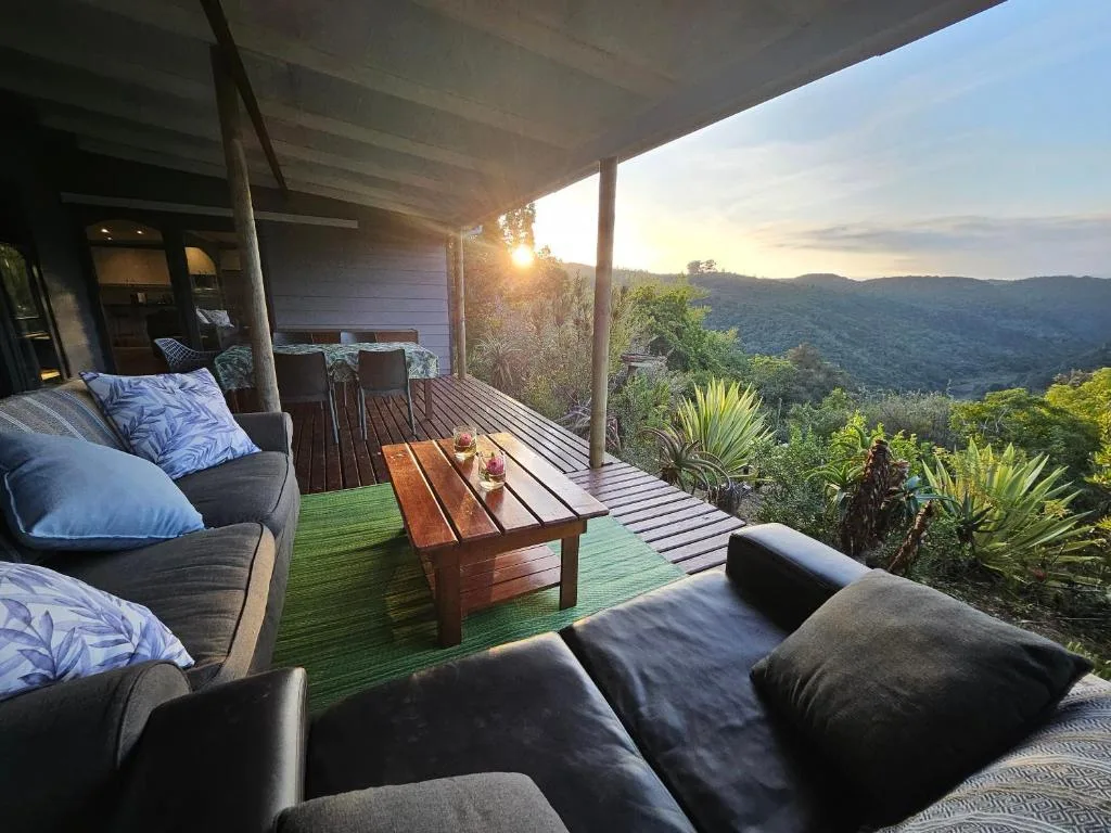 Covered outdoor deck with seating, wooden table, mountain valley views at sunset