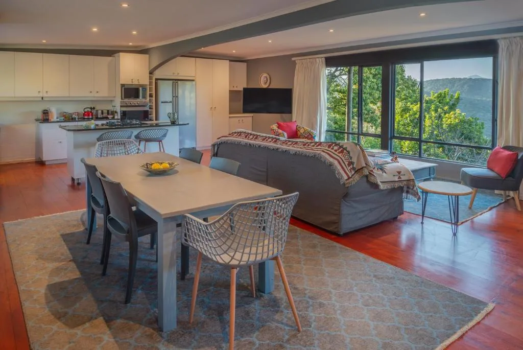Open-plan living area with dining table, sofa, and mountain views through large windows