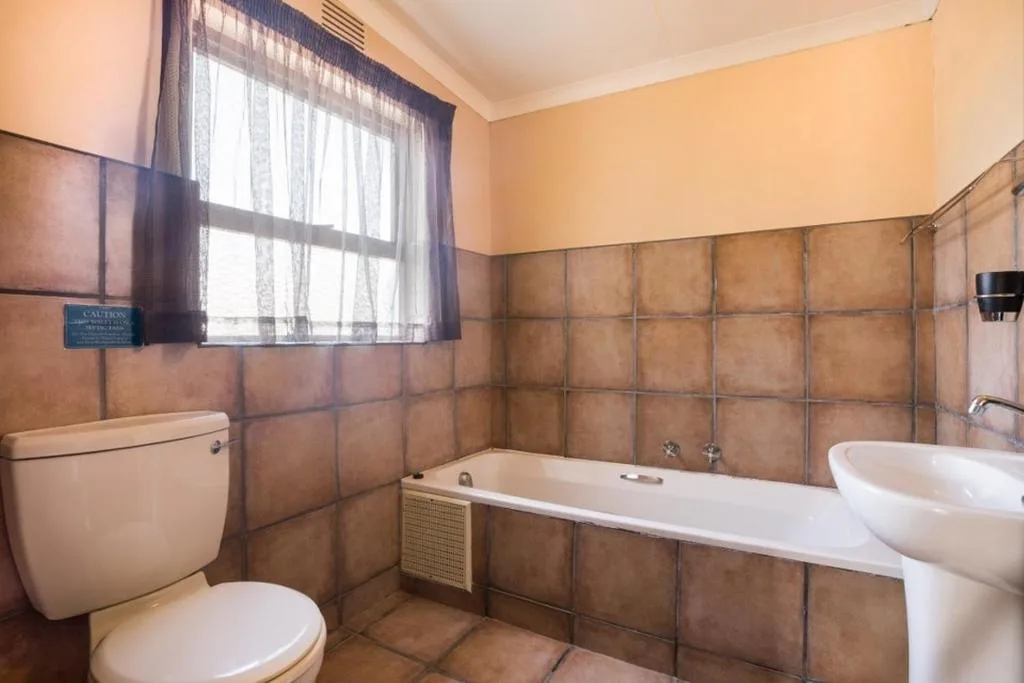 Bathroom with bathtub, toilet, sink, and brown tile walls