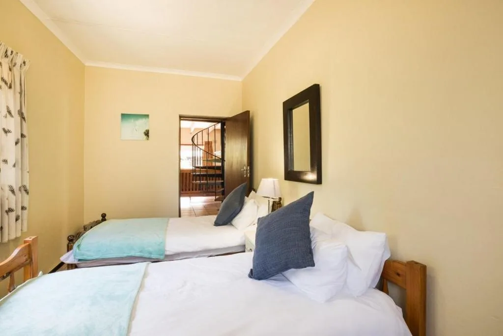 Twin beds with white linens and blue pillows in cheerful yellow room
