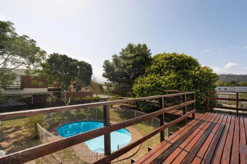 Wooden deck with pool view and surrounding garden landscape