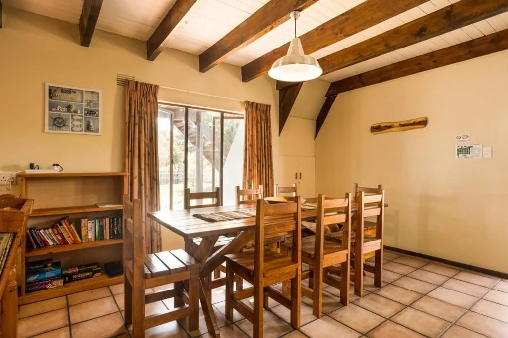 Dining area with wooden table, chairs, and exposed beam ceiling