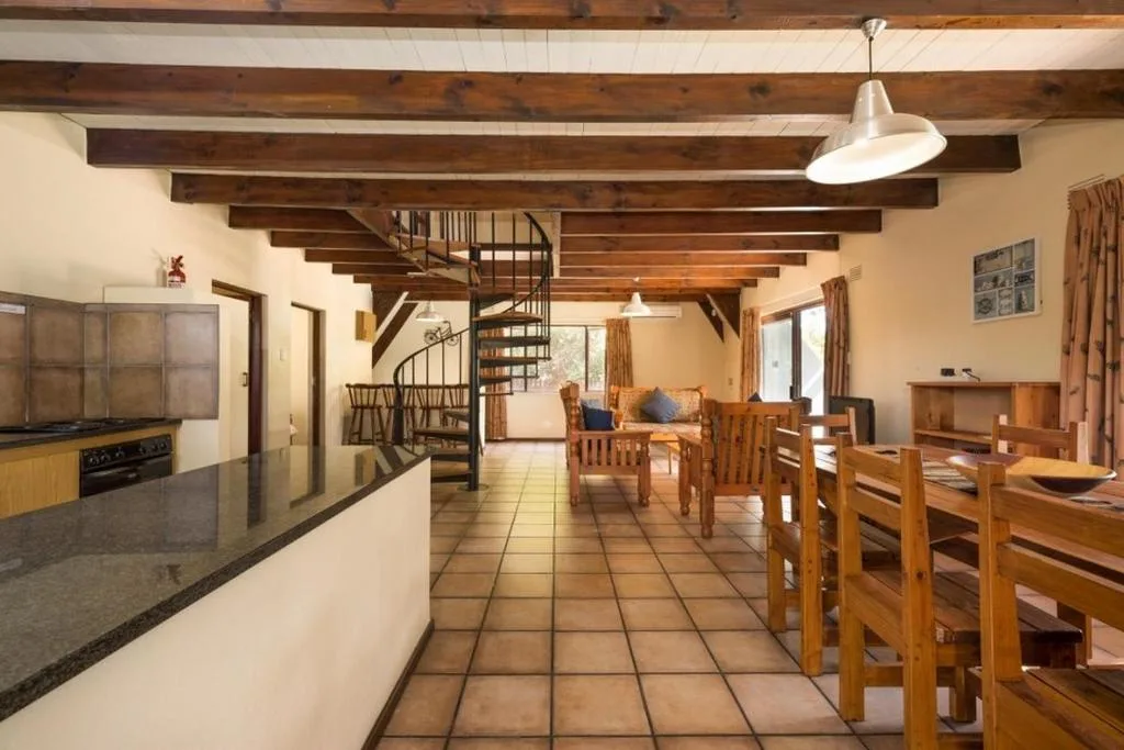 Open-plan dining area with wooden chairs and exposed beams throughout